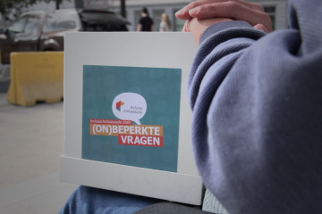 Foto van doos met (On)beperkte vragen in die op iemands schoot staat. 